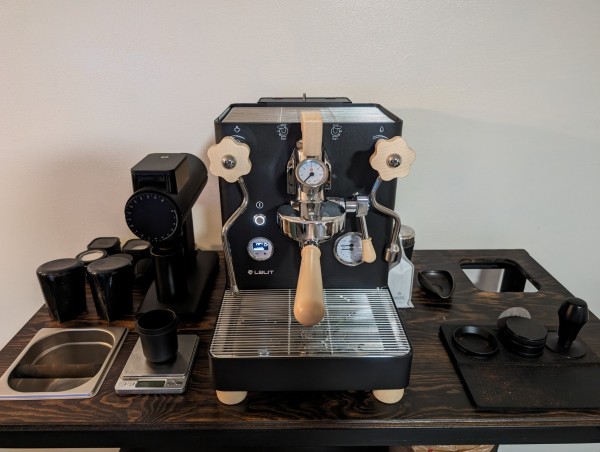 The matte black and maple Lelit Bianca espresso machine sitting on a wood coffee bar.