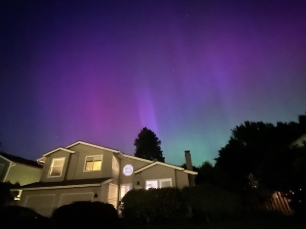 A house at night with a sky displaying aurora.