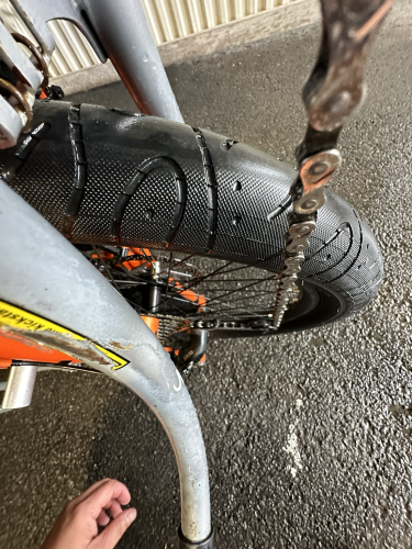Image straight down the chain of a Yuba e-bike standing on the back end with a big black tire behind the chain