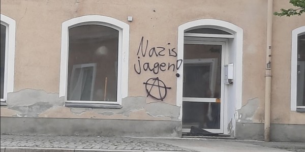 Häuserfassade eines verlassenen alten Hauses, an dessen Wand steht: Nazis jagen! Und ein Anarchie Zeichen drunter
