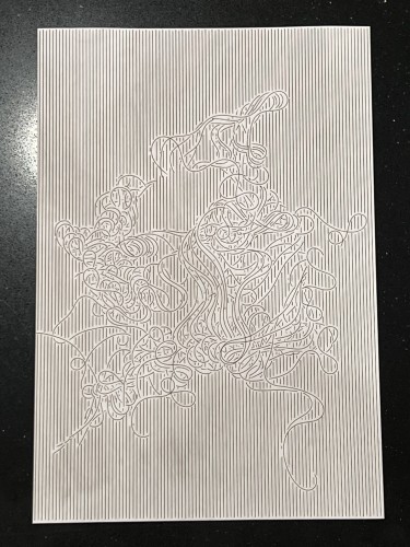 Laser engraved pattern made of tightly spaced vertical lines with a cluster of curly lines in the middle of the page. Some smudging from ash is visible on the page.