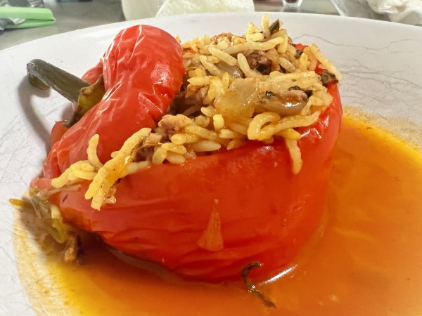 A white bowl with a roasted red pepper stuffed with rice and sausage