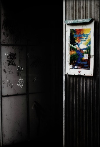 Looking at a brightly coloured poster on a exterior wall next to a recessed door.