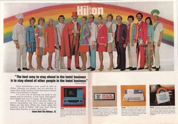 Vintage ad for Hilton hotels, advertising their new colorful uniforms. A photo of a line of hotel workers. They all have outfits in bold 1970s colors like avocado green or red-orange. Many of the outfits feature rainbow-colored stripes.