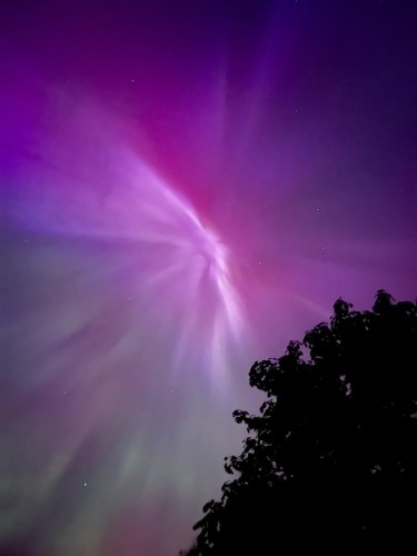 Purple red and green aurora that looks like the sky is ripping.  Photo credit to a family member who got the best shot.