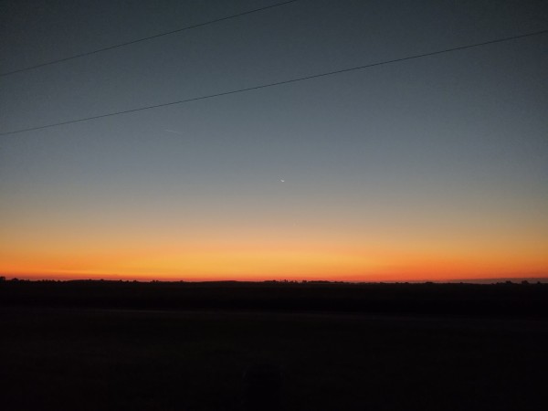 Sunrise over the corn field. This is the original orange creamsicle fade. Some might attempt to reproduce it, but this is the real deal. Dark orange on the horizon,then lighter, then light blue getting darker as you go up. No clouds, and just the faintest peek of a star right in the middle.