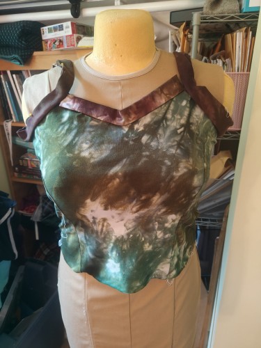 On a dressmaker's mannequin sits a princess seamed bodice in handdyed greens with brown straps and neck binding 
