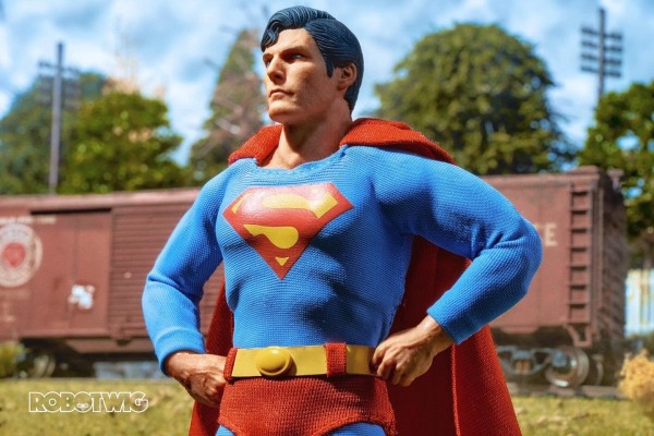 Superman stands proudly in front of a train carriage on a sunny day