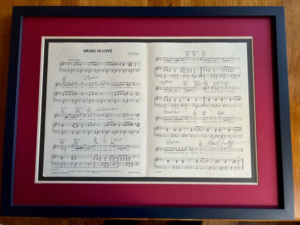 Signed sheet music in a black frame with a red border and a dark green mat inset.