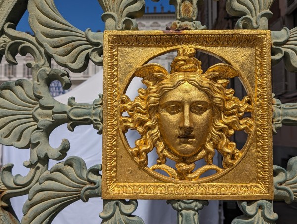 A gilded face set into an ornate fence