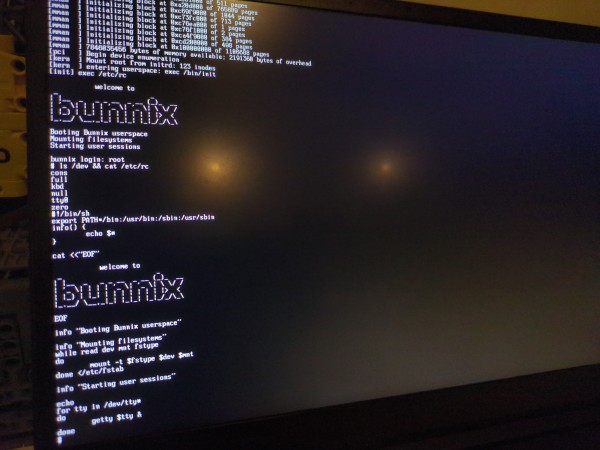 Picture of a laptop running an interactive Bunnix session. The user logs in as root and runs "ls /dev && cat /etc/rc".