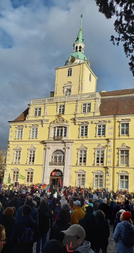 Menschenmenge vor dem Oldenburger Schloss, welches von der Sonne "erleuchtet" wird.