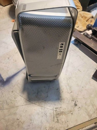 A Mac pro, resting upside down, with a case so badly mangled that you appear to be looking at a piece of scrap metal masquerading as a computer.