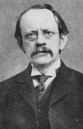 English physicist J J Thomson.

Black and white photo featuring J J Thomson sporting glasses and a mustache.