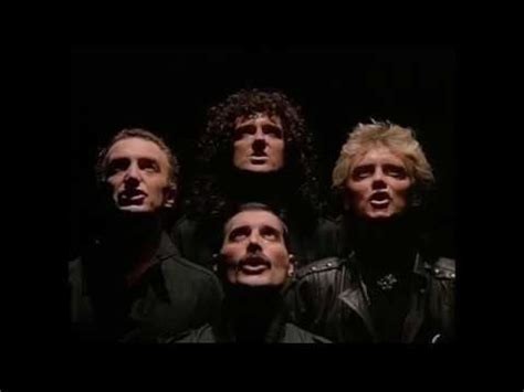 Classic shot of the heads of all 4 members of Queen looking upwards with a black background (One Vision)