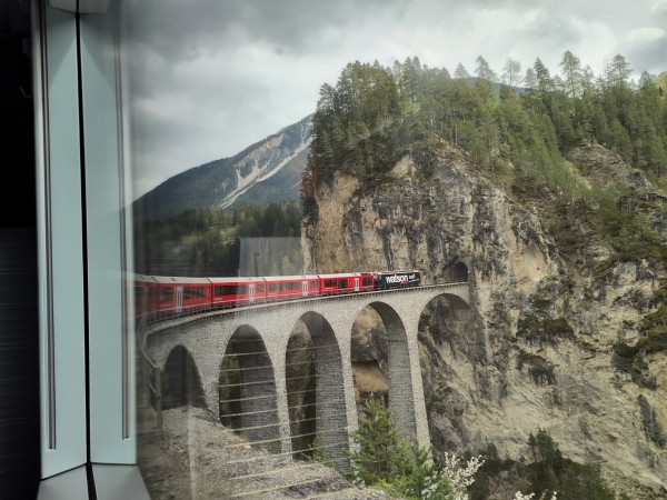 Foto. Ein roter Zug auf einer Brücke.
