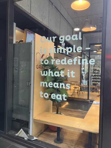 A sign in a cafe window saying our goal is simple to redefine what it means to eat 