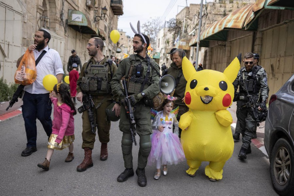 Armed Zionist settlers carrying asult rifles escort young children dressed for Easter through the streets of Hebron no one is allowed outside in the street while they are there.