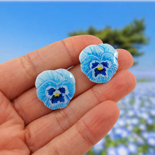 Puces d'oreilles éco-responsables en forme de petites pensées bleues pastel, réalisées en CD recyclé et peintes à la main par Savousépate