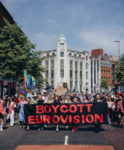 Huge crowd with Palestinian and South African flags march behind a banner reading BOYCOTT EUROVISION