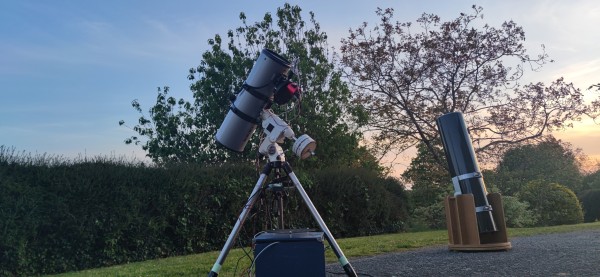 Au crépuscule, deux télescopes sont tournés vers le ciel, l'un est équipé pour l'astrophotographie, l'autre pour de l'observation visuelle 