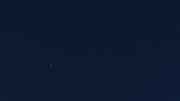 Aufnahme des Sternenhimmels, darauf eine lichtschwache Strichspur, deren Helligkeit von rechts nach links (in Flugrichtung) abnimmt.