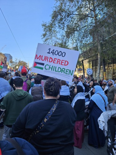 Huge crowds with placards and banners.  The placard in the foreground reads 14,000 MURDERED CHILDREN