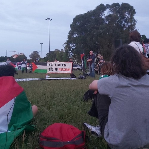 Tents and students wrapped in Palestinian flags hold a huge banner reading NO TO WAR, NO TO MASSACRE