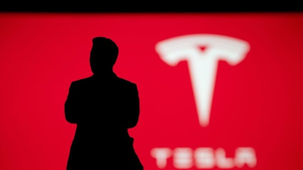 Rote Wand mit dem Tesla Logo im Hintergrund, davor die schwarze Silhouette von Elon Musk.