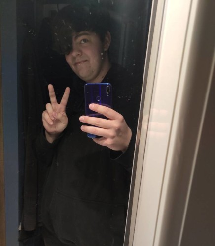A mirror selfie with me peeking into the mirror, my left eye covered by my dark brown hair. I'm also smiling slightly and doing a "V" gesture with my second hand (the one not occupied by holding the phone)