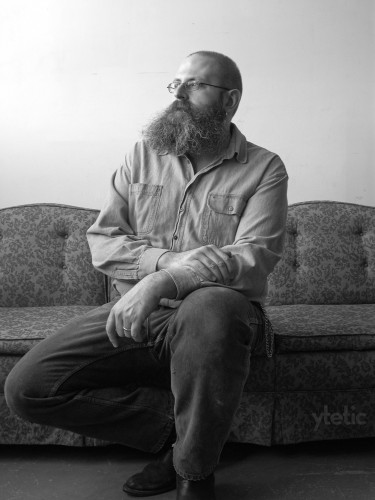 Four BW photos in studio.
1. Sitting looking sideways, on the amazing vintage couch.