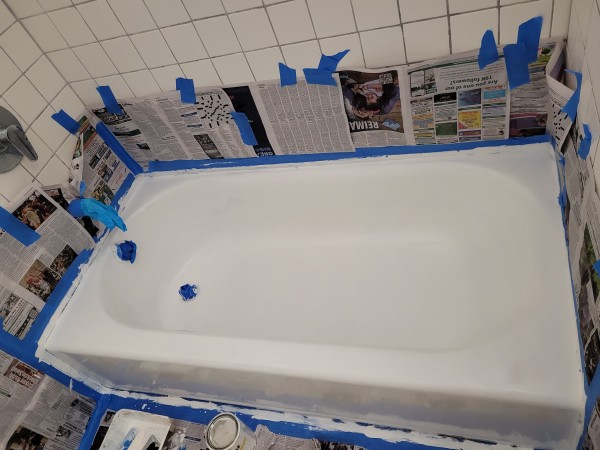Bathroom tub surrounded by newspaper. Tub is coated with epoxy tub and tile paint.