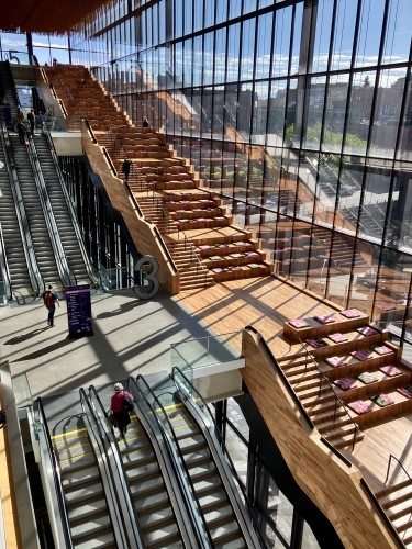 A interior shot of part of the Seattle Convention Center "Summit" building, showing the massive star case and escalators spanning 4 floors with a huge glass expanse overlooking the city.