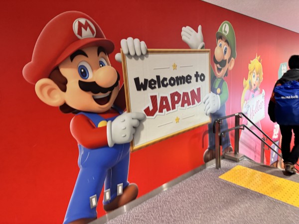 Mario and Luigi holding a “Welcome to Japan” sign