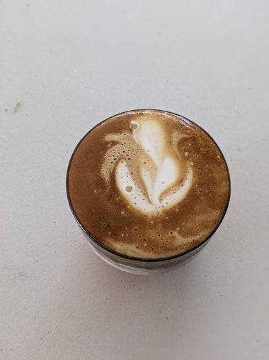 Flat white coffee in a cup with poorly executed latte art