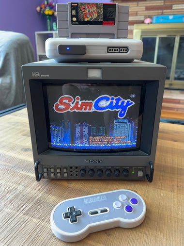 A Sony PVM 8045Q with an Analogue Super Nt on top with SimCity for SNES in it. The PVM is showing the title screen of SimCity.