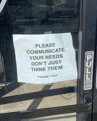 piece of paper stuck on a glass door (with a "pull" sign above the handle) that reads: "please communicate your needs, don’t just think them - thank you !"