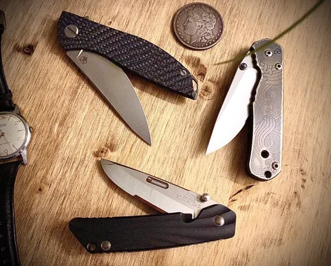 3 pocket knives on a wooden background