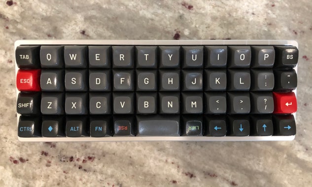 A 40% ortholinear keyboard with grey alphanumeric keys with white legends, dark grey modifiers with red, green, and blue legends, and a red escape key and enter key.