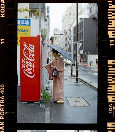 woman in a kimono buying a drink from a vending machine in the rain