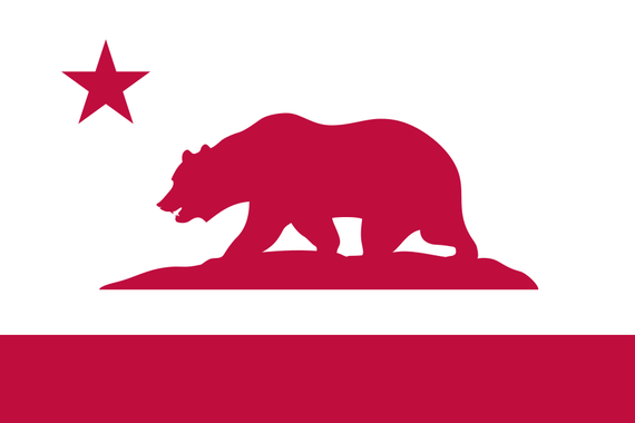 A white, 2:3 flag with a red star in the top left, a red stripe at the bottom, and a red silhouette of a bear on a patch of grass.