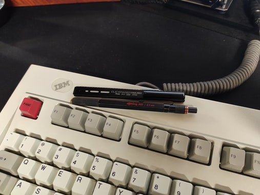 A well worn Rotring 800 and Pentel Clic Eraser sitting atop an IBM keyboard