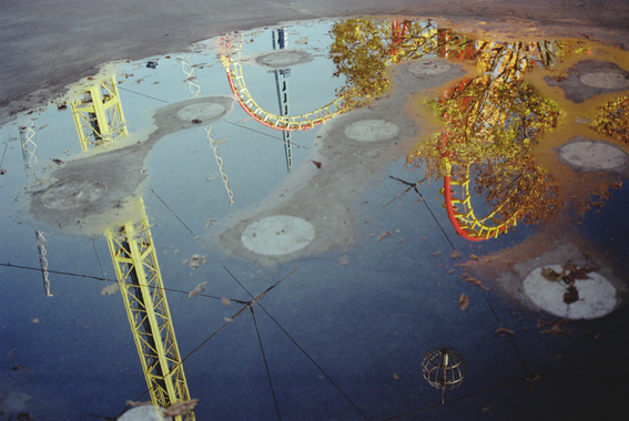 Reflection of a fairground rollercoaster in a puddle.