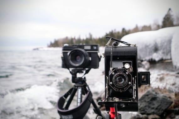 Two cameras next to a lake