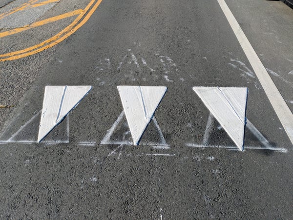 newly installed "shark's teeth" street markings, on top of temporary spray-painted versions that were carefully laid out upside down