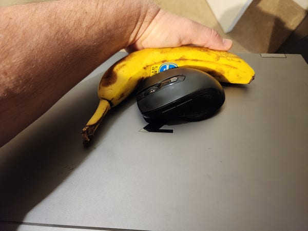 A laptop being carried one-handed. I've nestled a banana against the laptop to cradle the mouse while in transit.