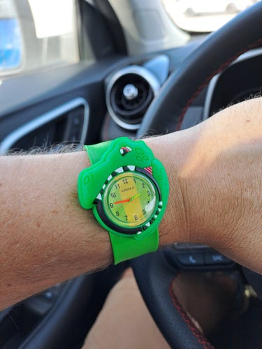 A green rubber dinosaur watch on a man's wrist.