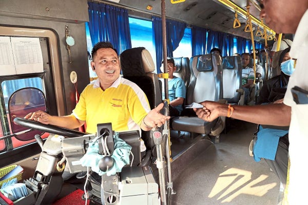 A passenger paying for bus fare to the bus captain when boarding a bus. / Photo from linked article.