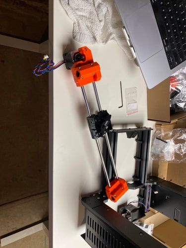 An incomplete 3D printer assembly on a table with various components and tools, including a laptop, scattered around it.

Specifically the X axis assembly