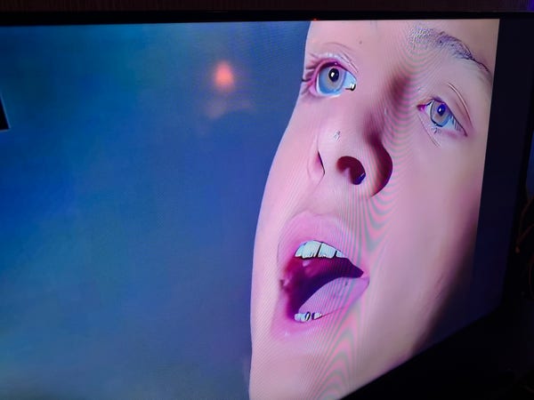 Photo of a tv showing the ai-distorted face of a young pop singer